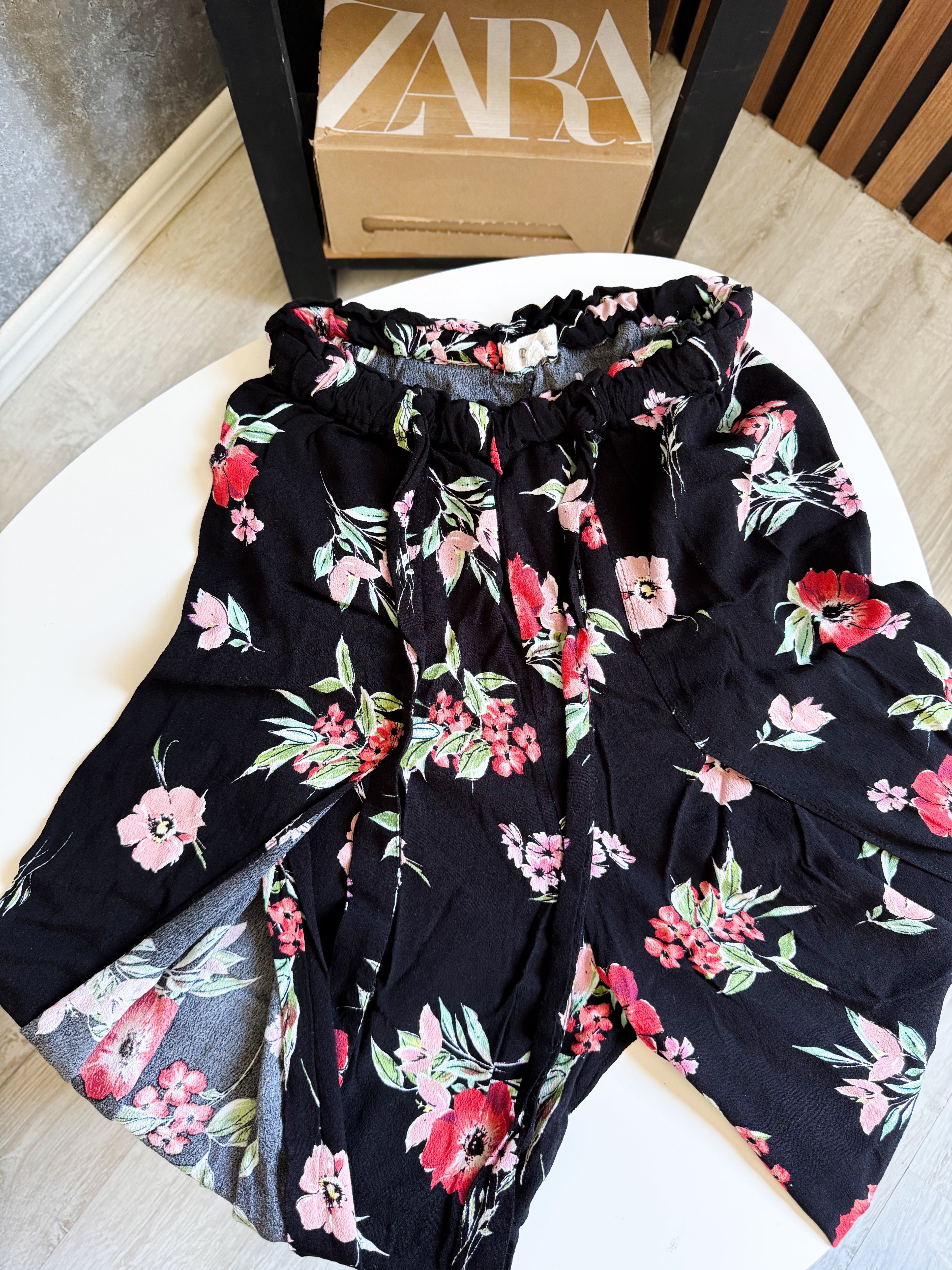 Pantalón suelto negro, abierto y floreado con lazo